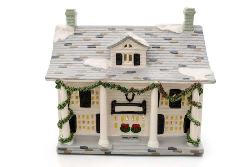 Ceramic Christmas village house with porch columns, garland, and snow-covered roof
